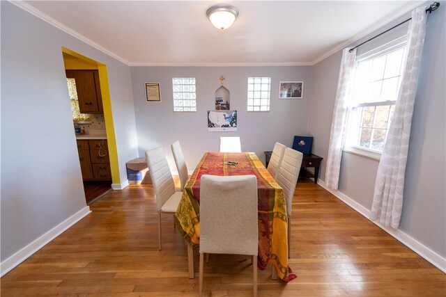 dining area with a wealth of natural light, crown molding, and hardwood / wood-style flooring