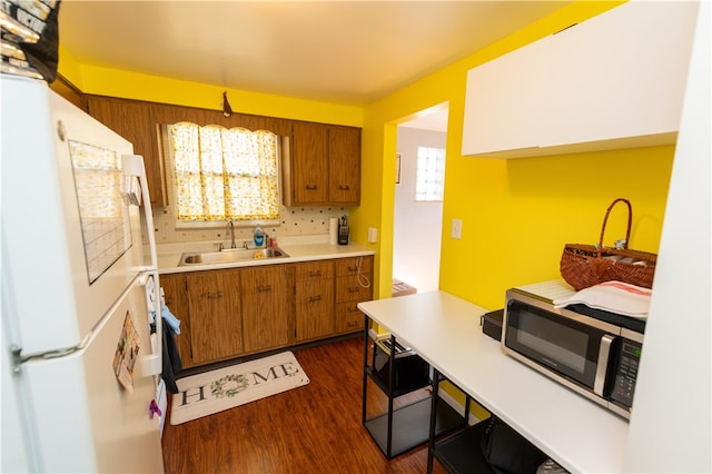 kitchen with dark hardwood / wood-style floors, sink, backsplash, and white refrigerator