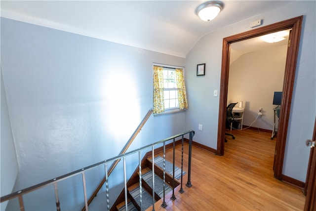 staircase with hardwood / wood-style floors and vaulted ceiling