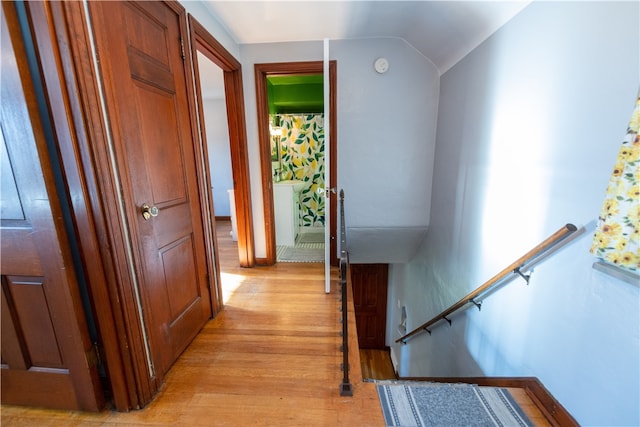 hallway with vaulted ceiling and light wood-type flooring