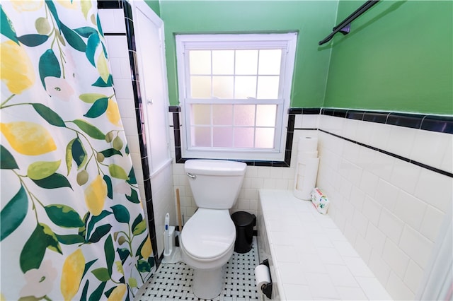 bathroom featuring toilet, tile patterned floors, tile walls, and curtained shower