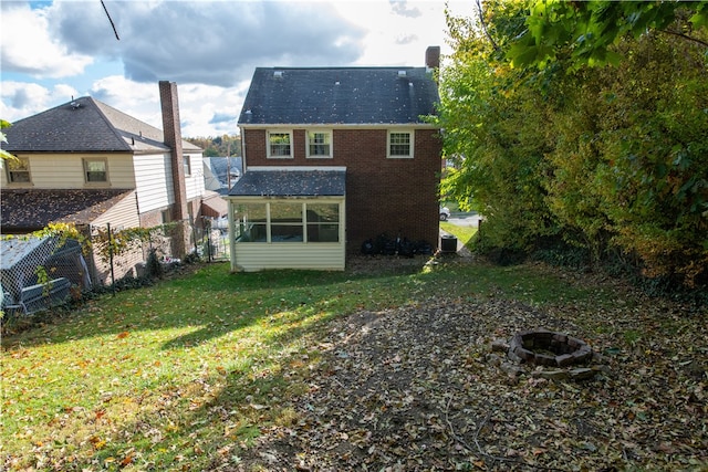 rear view of house featuring an outdoor fire pit, a yard, and central AC unit