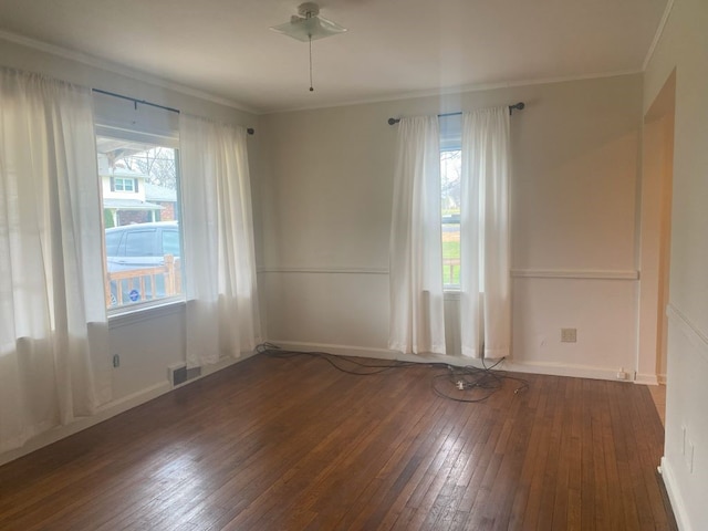 empty room with dark hardwood / wood-style floors, a wealth of natural light, ornamental molding, and ceiling fan