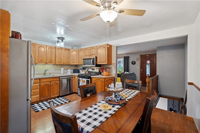 kitchen featuring backsplash, sink, light hardwood / wood-style flooring, ceiling fan, and stainless steel appliances