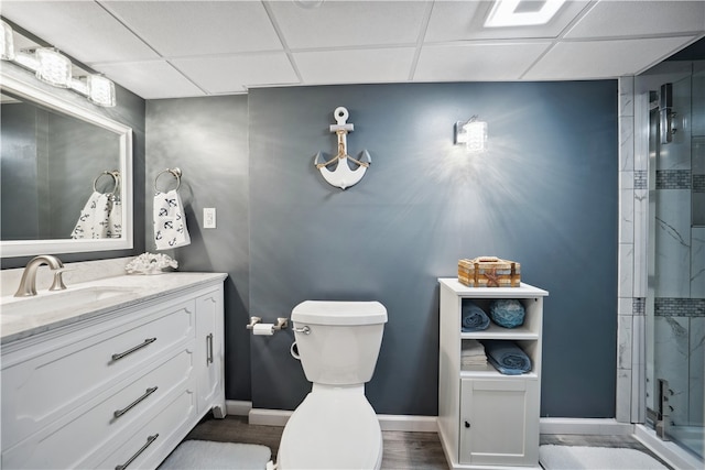 bathroom with walk in shower, a drop ceiling, vanity, hardwood / wood-style floors, and toilet