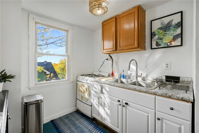 kitchen featuring sink, white range with gas stovetop, and white cabinets