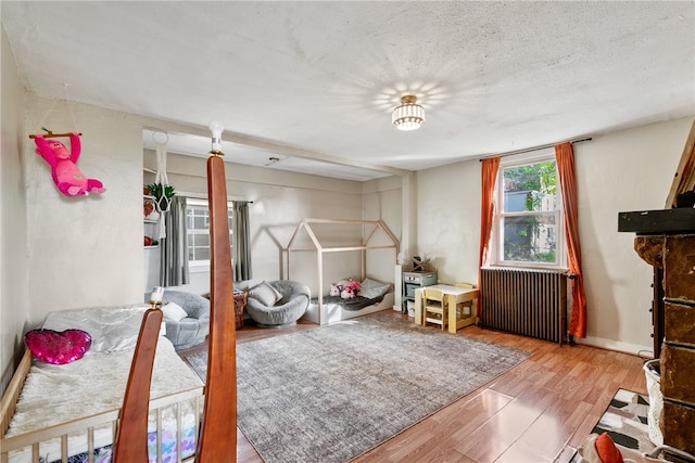 bedroom featuring radiator heating unit, a textured ceiling, and light wood-type flooring