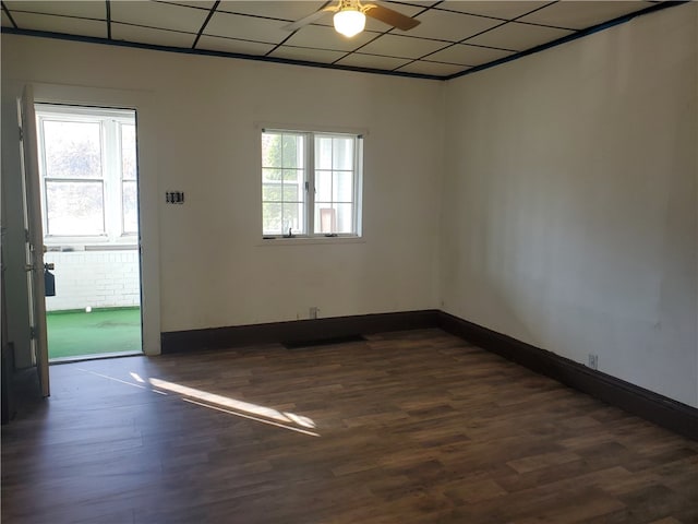 unfurnished room with a drop ceiling, dark hardwood / wood-style floors, plenty of natural light, and ceiling fan