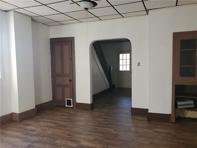 unfurnished room featuring dark wood-type flooring and a drop ceiling