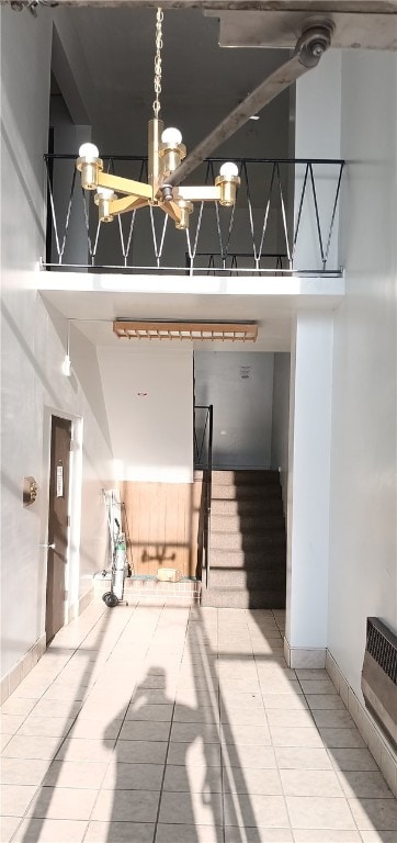 stairs featuring a high ceiling, a notable chandelier, and tile patterned floors