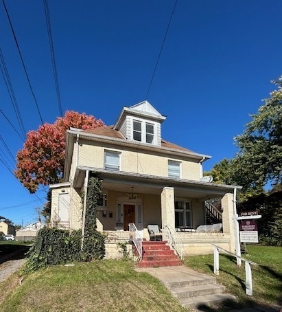 traditional style home featuring covered porch and a front yard
