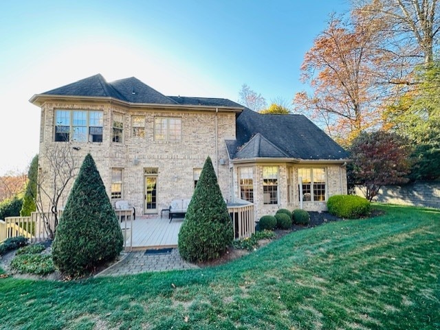 rear view of property with a deck and a lawn