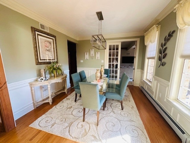 dining room with hardwood / wood-style floors, a notable chandelier, ornamental molding, and a baseboard radiator