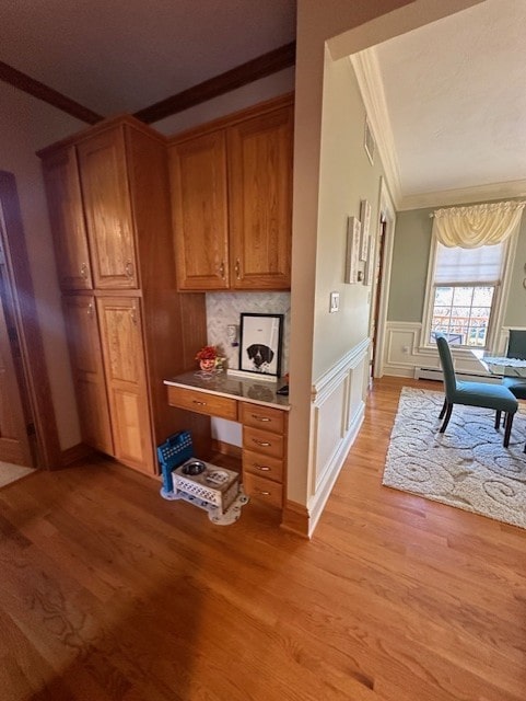 interior space featuring backsplash, light hardwood / wood-style floors, and crown molding