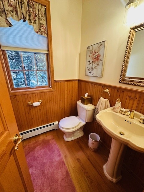 bathroom with baseboard heating, wooden walls, hardwood / wood-style floors, and toilet