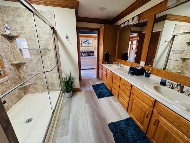 bathroom with wood-type flooring, vanity, ornamental molding, and a shower with shower door