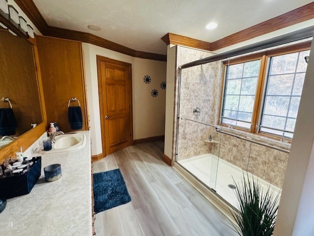 bathroom with vanity, wood-type flooring, a shower with shower door, and crown molding