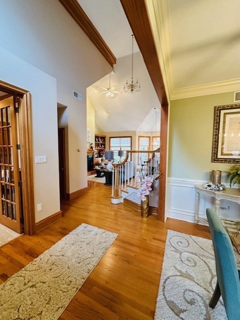 interior space featuring crown molding, beam ceiling, high vaulted ceiling, an inviting chandelier, and light hardwood / wood-style floors