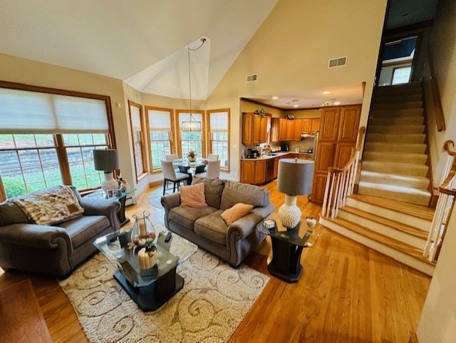 living room featuring high vaulted ceiling and light hardwood / wood-style flooring