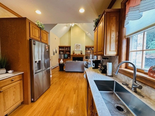 kitchen featuring sink, a baseboard radiator, stainless steel refrigerator with ice dispenser, light hardwood / wood-style floors, and lofted ceiling