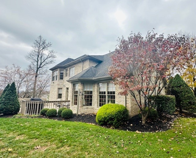 rear view of property featuring a lawn and a wooden deck