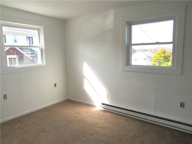 carpeted empty room featuring plenty of natural light and baseboard heating