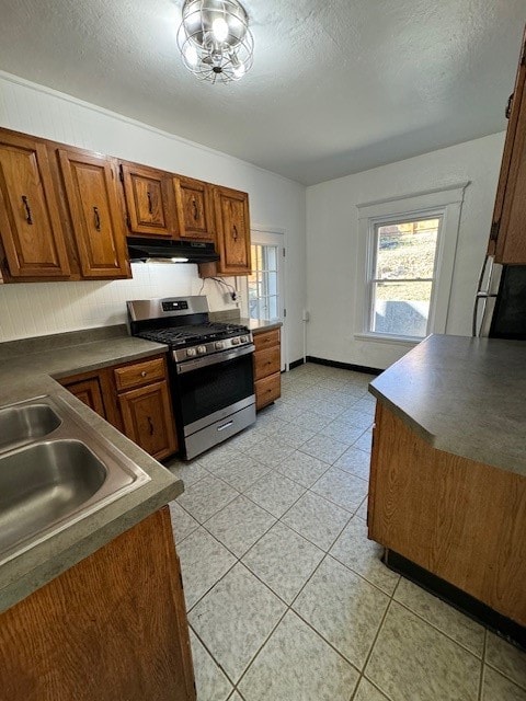 kitchen featuring a textured ceiling, sink, light tile patterned floors, and stainless steel gas range