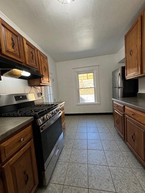 kitchen featuring stainless steel gas range oven, tasteful backsplash, a textured ceiling, and light tile patterned floors