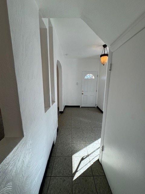 interior space with vaulted ceiling and dark tile patterned flooring