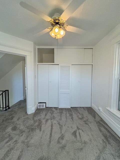 unfurnished bedroom featuring carpet floors, two closets, a textured ceiling, and ceiling fan