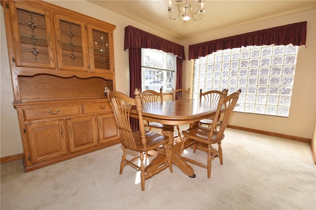 dining area featuring light colored carpet, a healthy amount of sunlight, and a notable chandelier