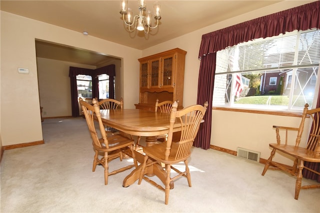 dining space with a chandelier, light colored carpet, and plenty of natural light