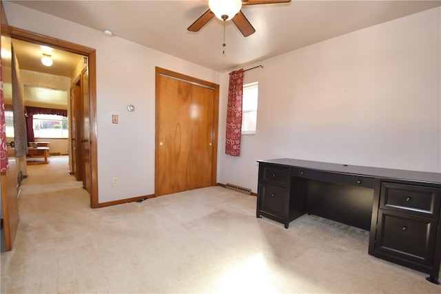 office space with built in desk, light carpet, and ceiling fan