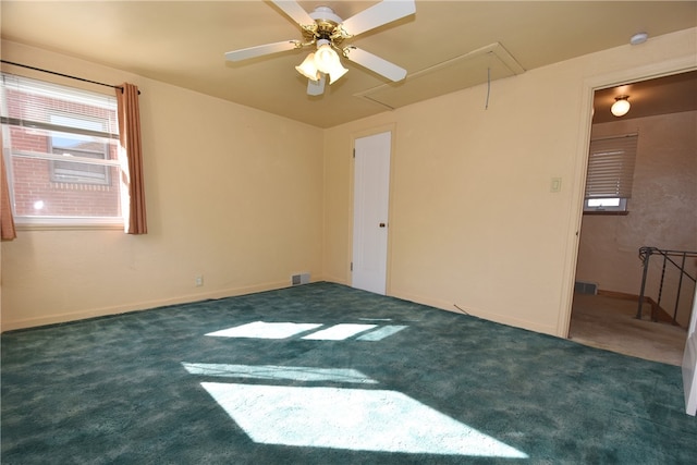 spare room featuring dark colored carpet and ceiling fan