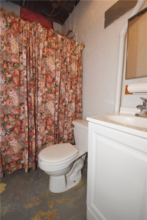 bathroom with toilet, concrete flooring, and vanity