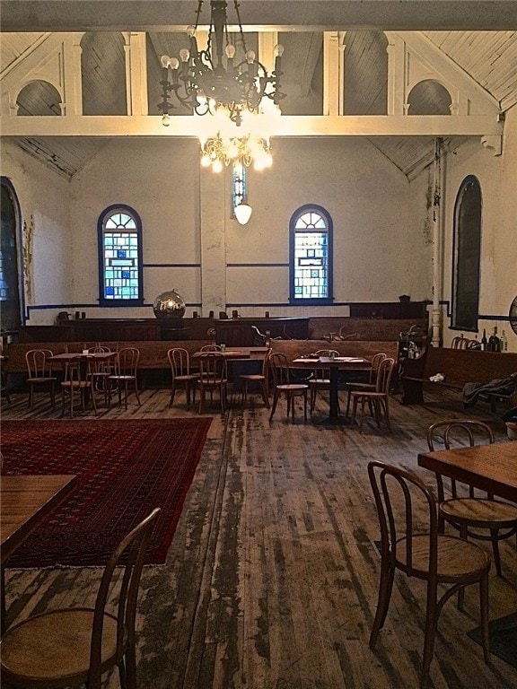 dining room with hardwood / wood-style floors, a chandelier, high vaulted ceiling, and a healthy amount of sunlight