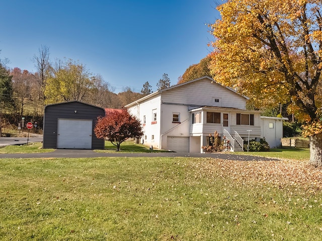 view of front of house featuring a garage, a front lawn, and an outbuilding