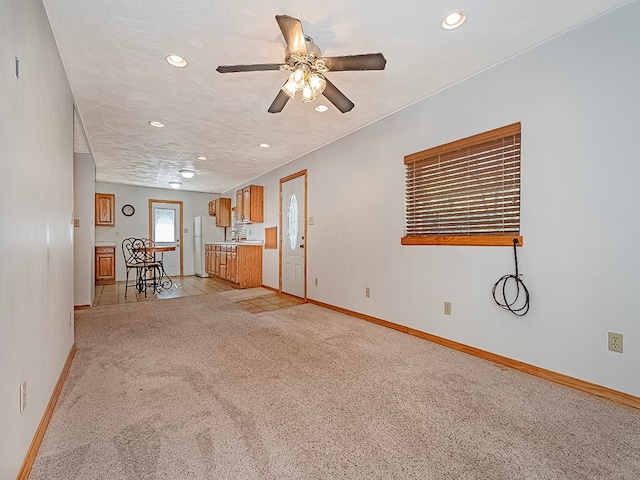 unfurnished living room with light carpet, a textured ceiling, and ceiling fan