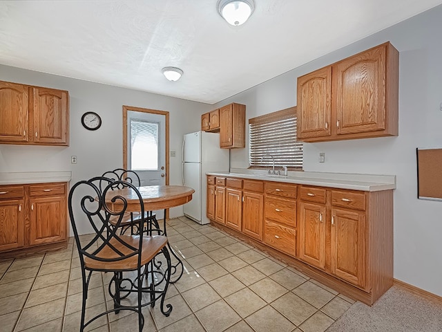 kitchen with white fridge, light tile patterned floors, and sink