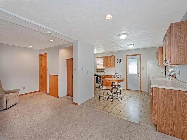 kitchen featuring sink, a kitchen bar, stainless steel range oven, a textured ceiling, and light carpet