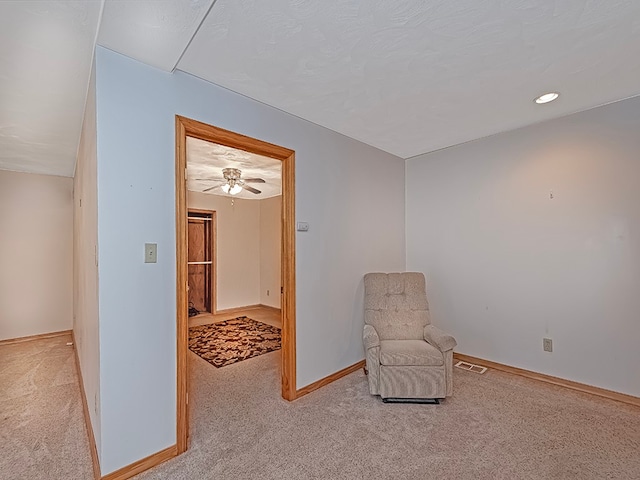 living area featuring light carpet and ceiling fan