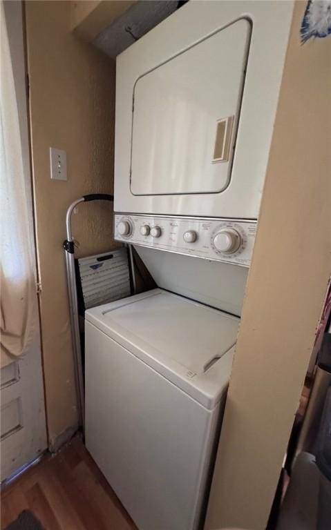 laundry area with hardwood / wood-style floors and stacked washer / dryer