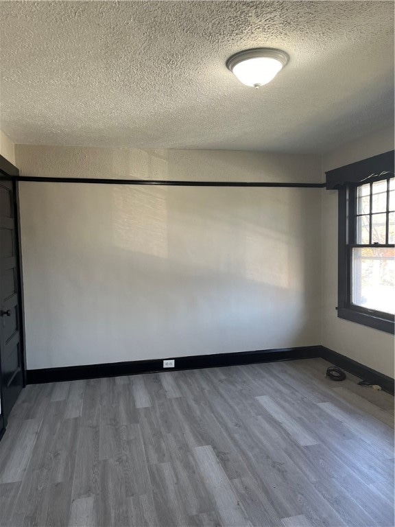 empty room with hardwood / wood-style floors and a textured ceiling