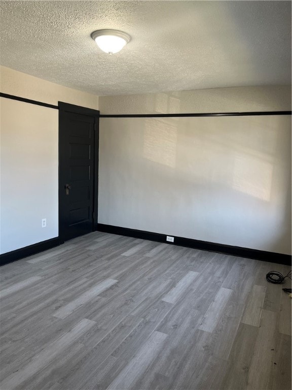 unfurnished room featuring hardwood / wood-style flooring and a textured ceiling