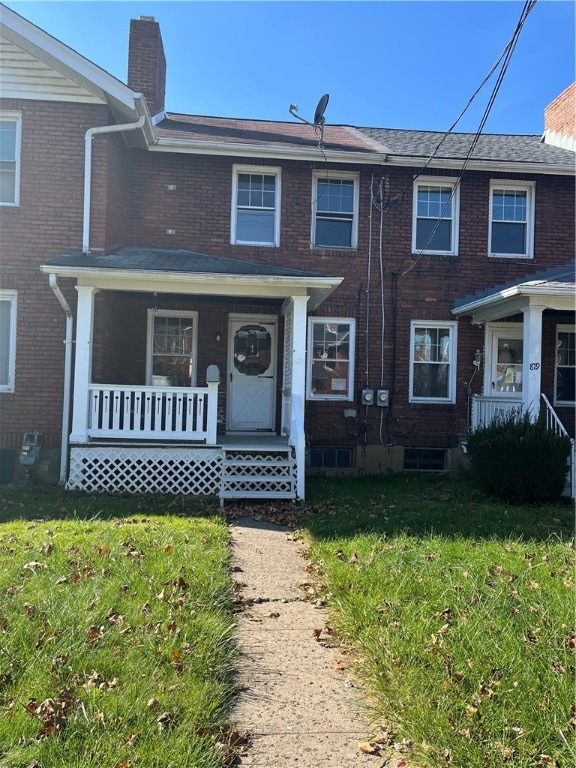 view of property with covered porch and a front lawn