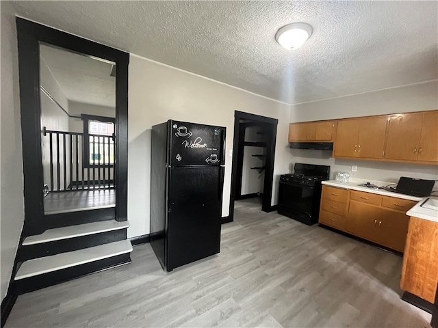 kitchen featuring light hardwood / wood-style floors, black appliances, and a textured ceiling