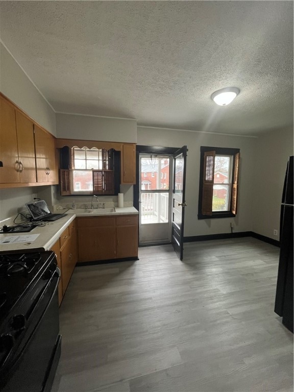 kitchen with plenty of natural light, black appliances, a textured ceiling, and light hardwood / wood-style flooring