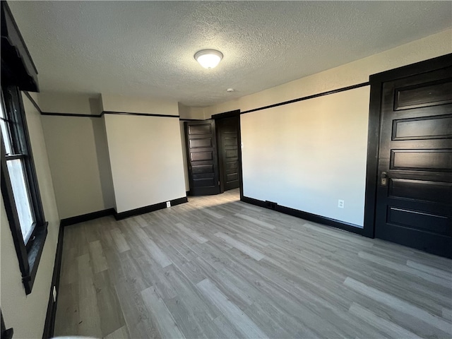 unfurnished bedroom with light hardwood / wood-style floors and a textured ceiling