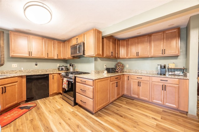 kitchen with light stone countertops, stainless steel appliances, and light hardwood / wood-style floors