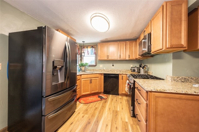 kitchen featuring hanging light fixtures, light stone counters, a textured ceiling, light hardwood / wood-style floors, and stainless steel appliances